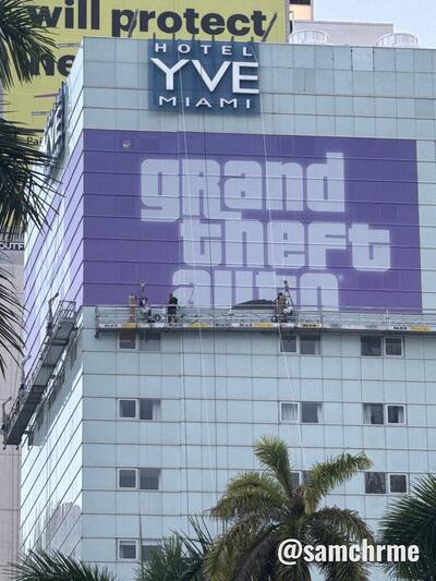 Fachada do Hotel YVE Miami com a lona roxa de GTA 6 e trabalhadores em andaimes durante a instalação