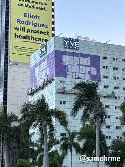 Hotel YVE Miami visto da rua, com o logotipo roxo de GTA 6 na fachada e palmeiras em primeiro plano