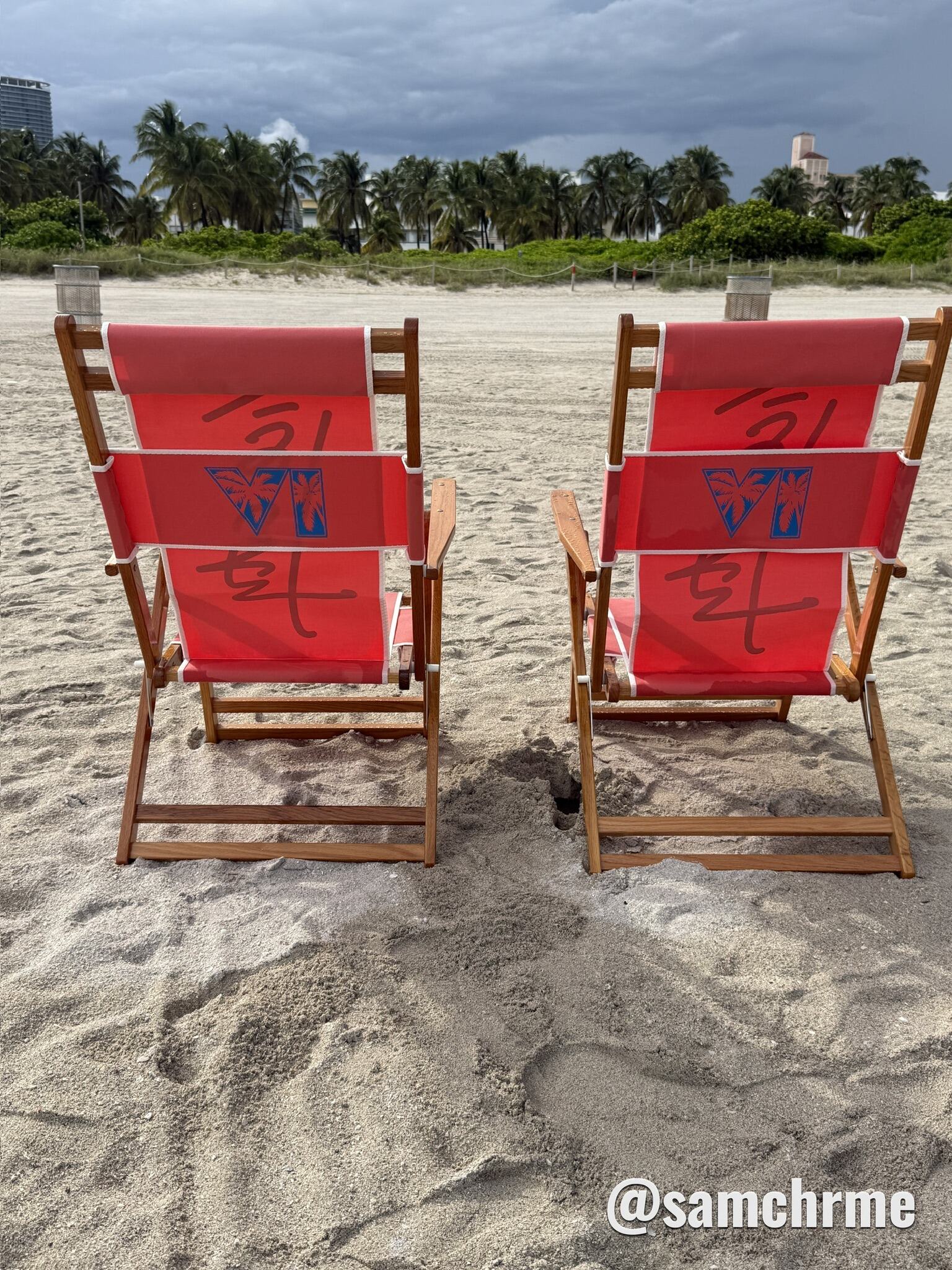 Duas cadeiras de praia vermelhas com o logotipo VI de GTA 6 nas costas, na areia de Miami Beach