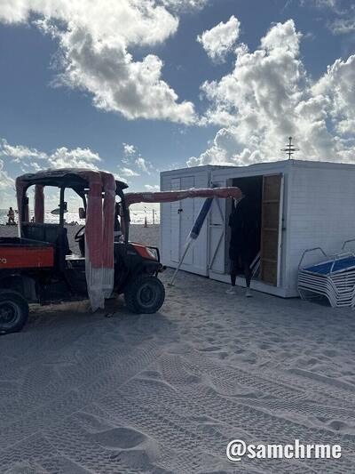 Veículo utilitário vermelho estacionado perto da cabine branca de apoio, na areia