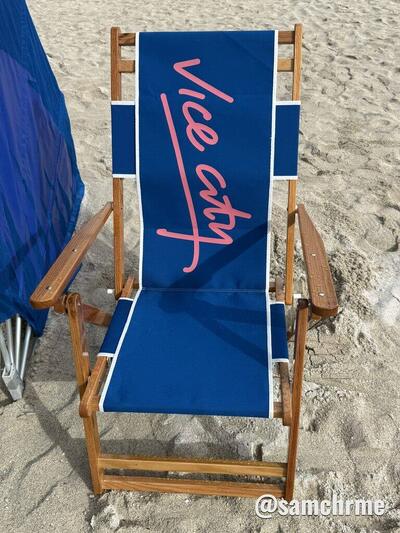 Cadeira de praia azul com "Vice City" em rosa, em letra cursiva, no encosto