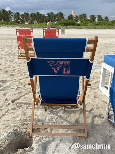 Cadeira de praia azul com o logotipo VI de GTA 6 nas costas e cadeiras vermelhas ao fundo