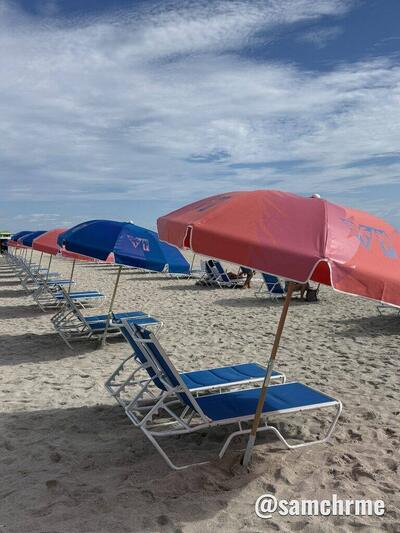 Guarda-sol vermelho e espreguiçadeiras azuis alinhados na areia de Miami Beach