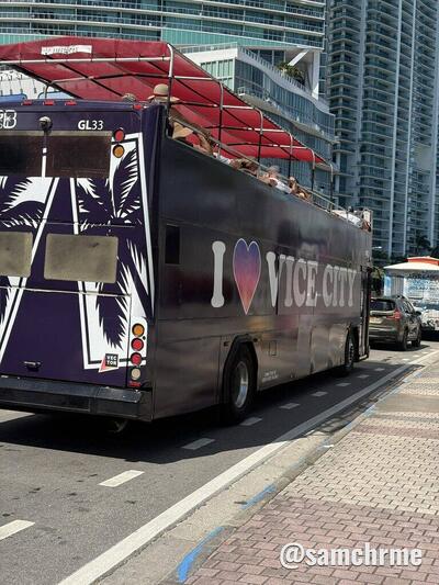 Traseira do ônibus "I ♥ Vice City", com palmeiras estampadas e arranha-céus ao fundo