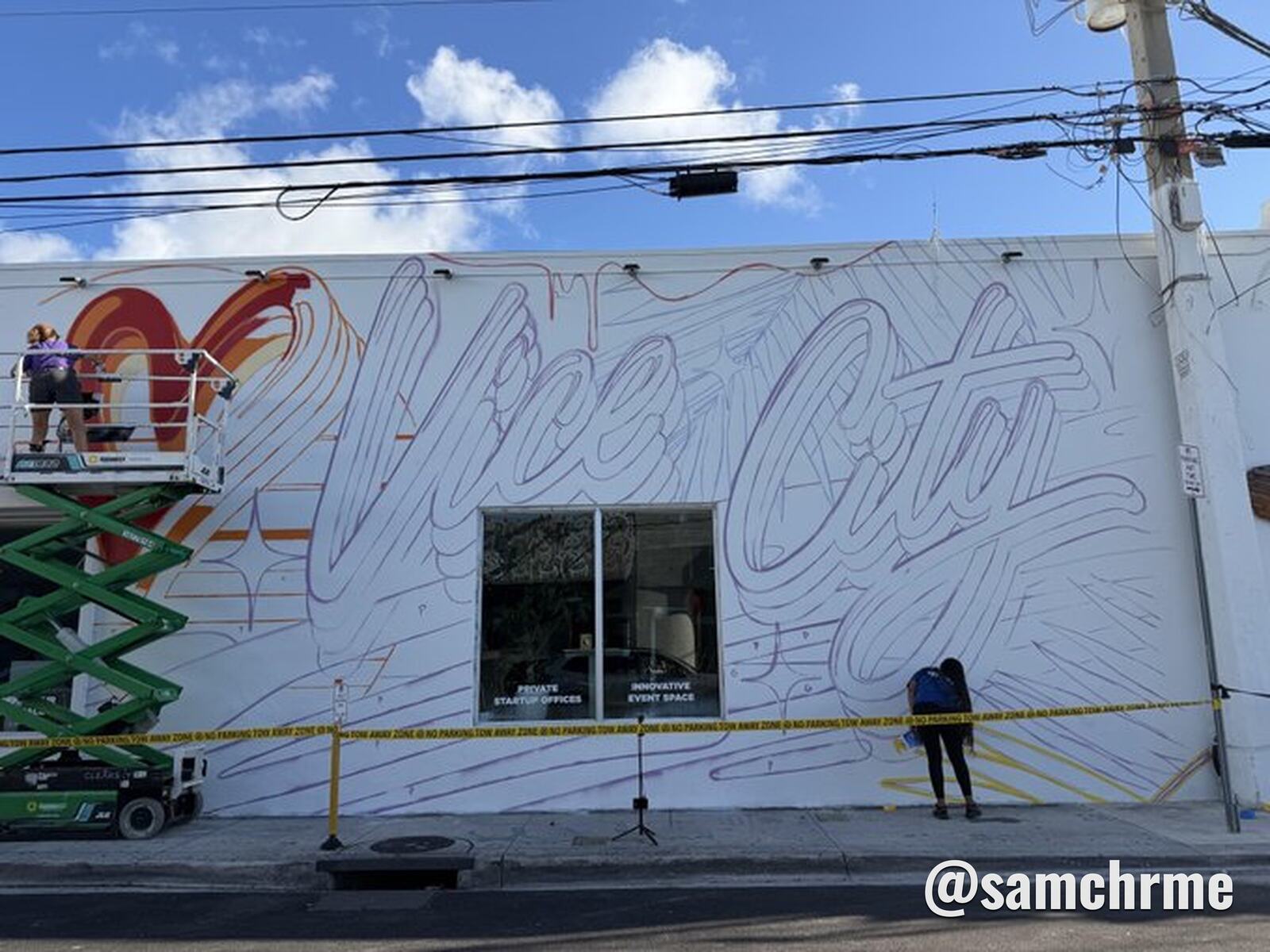 Contorno do mural "Vice City" desenhado a tra&ccedil;o numa parede branca, com artistas em plataformas elevat&oacute;rias