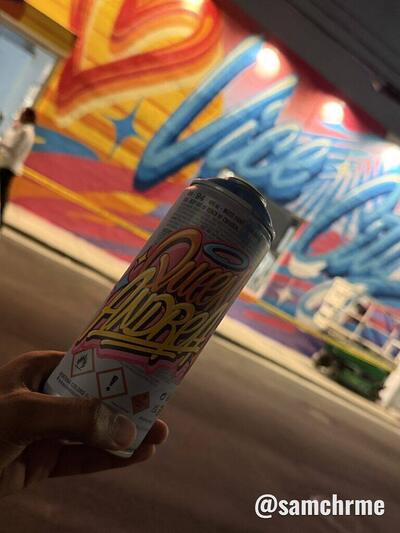 Lata de spray de desenho colorido segurada à frente do mural "We ♥ Vice City" iluminado