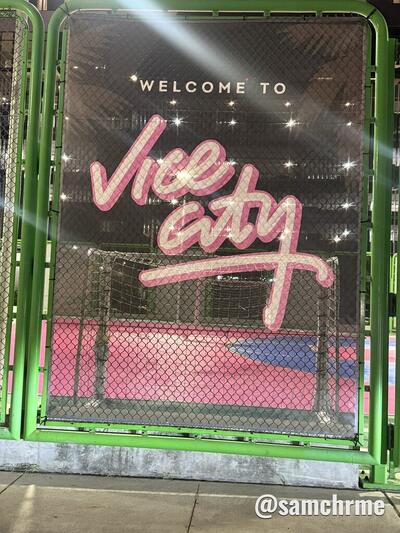 Lona "Welcome to Vice City" na grade verde da quadra rosa do Underline, em Brickell, à noite