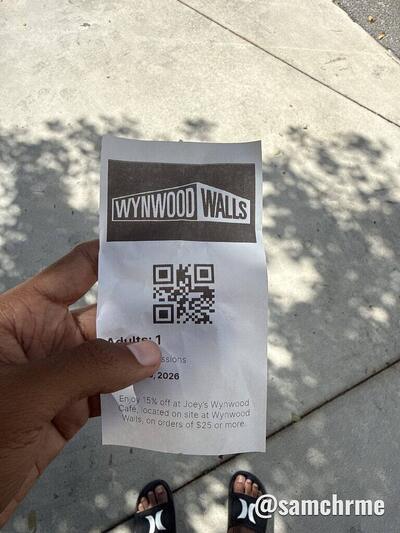 Ingresso de papel do Wynwood Walls com QR code, segurado numa calçada